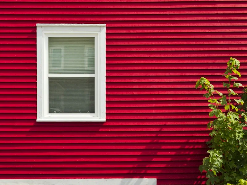 Red painted house siding with white window trim
