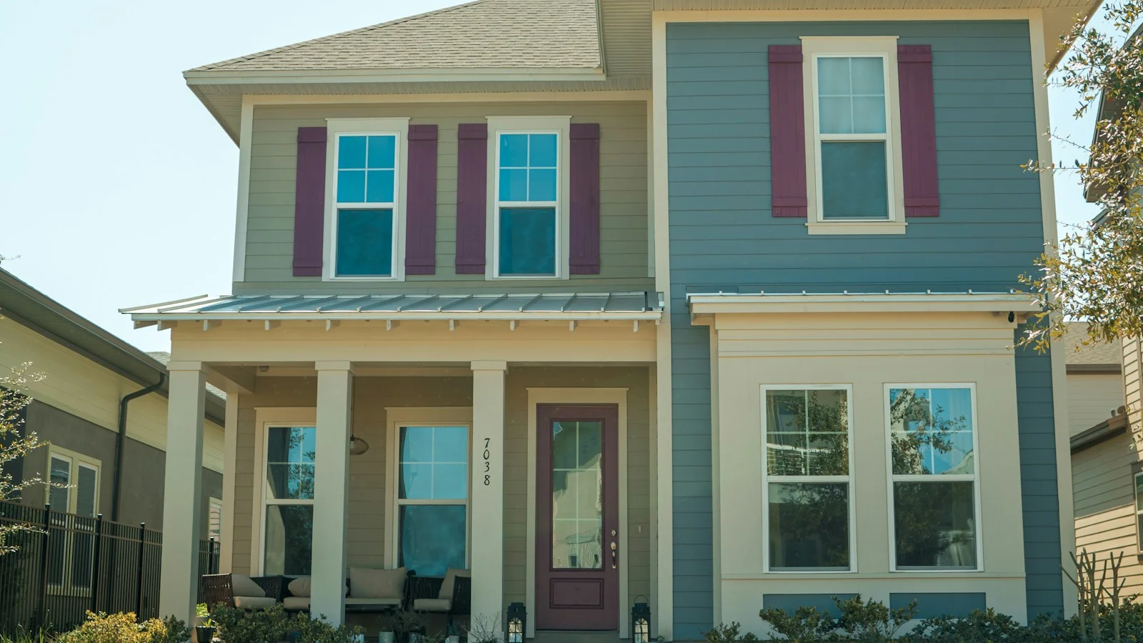 Two-story house with blue siding, red shutters and a front porch