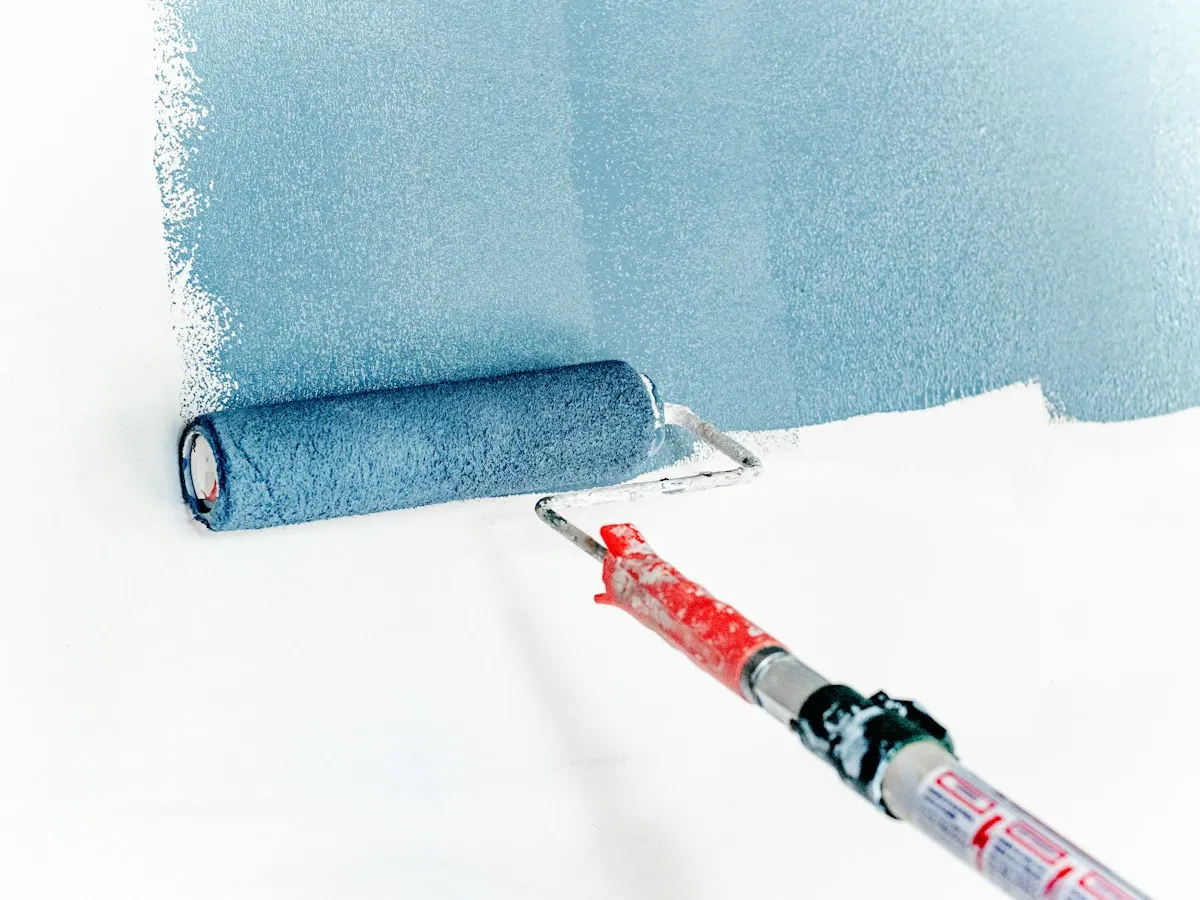 Paint roller applying light blue paint to a wall